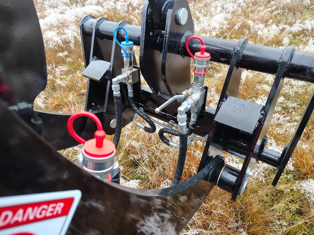 Hydraulanslutningar med röda och blå skydd vid redskapsfästet