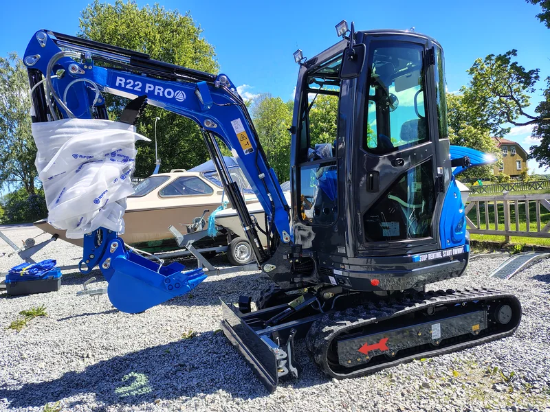 Rippa R22 med hytt, skopa och schaktblad på gårdsplanen